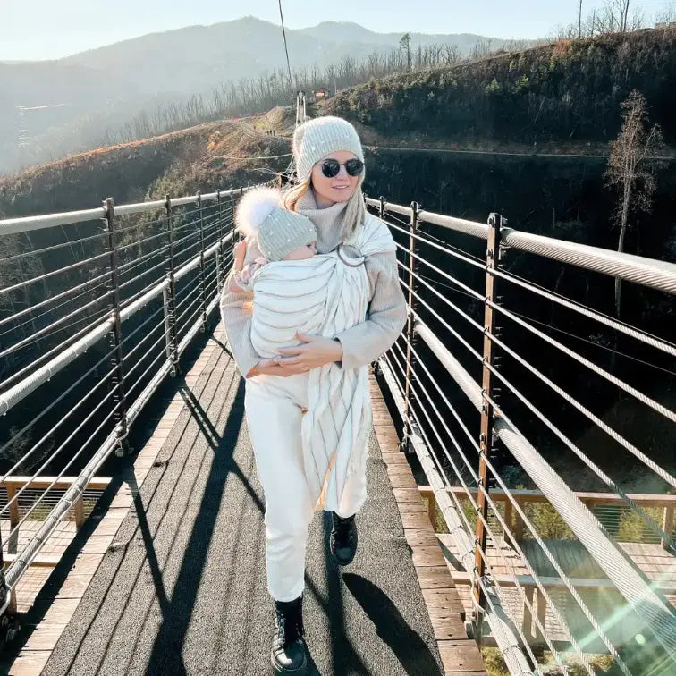 Mother holding child in a ring sling in winter