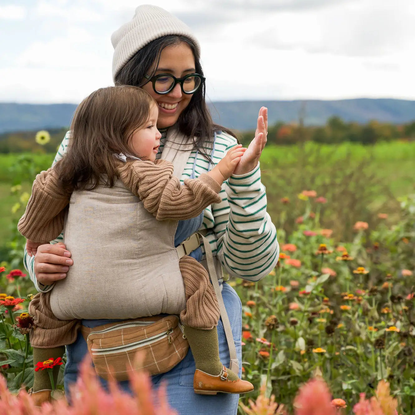 Woman babywearing her small toddler in a field of flowers
