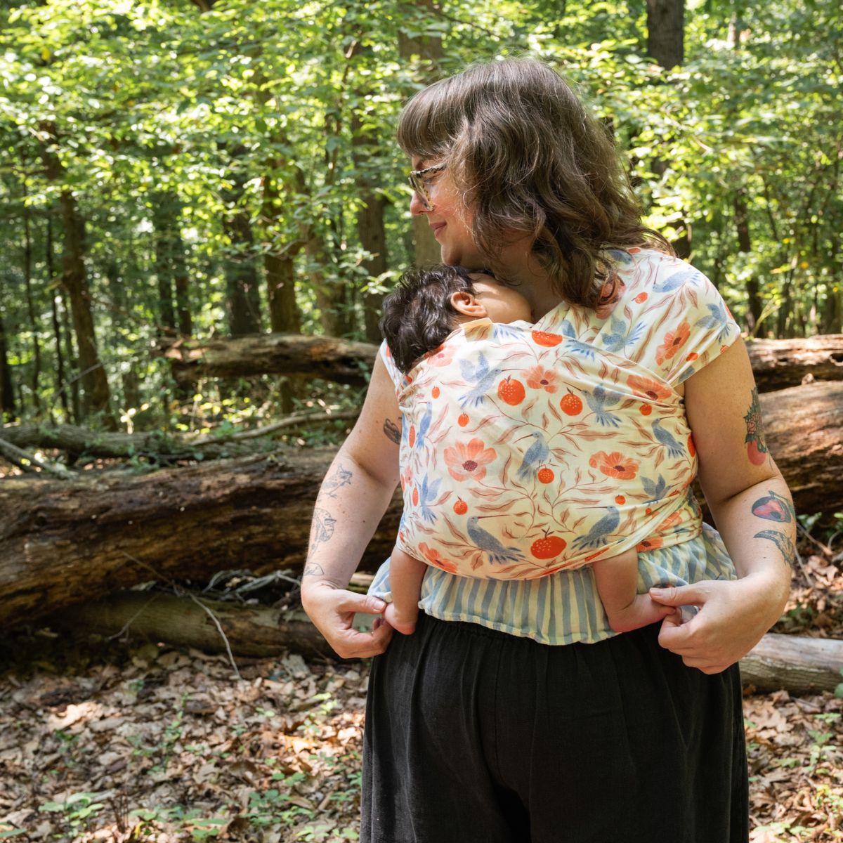A plus-size white woman looks to the side while wearing an infant in a hope&plum Ambrosia stretchy baby wrap