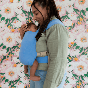 A close up shot of a BIPOC newborn worn on their mother’s front in a hope&plum Sprout Newborn Carrier.