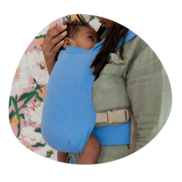 A close up shot of a BIPOC newborn worn on their mother’s front in a hope&plum Sprout Newborn Carrier.