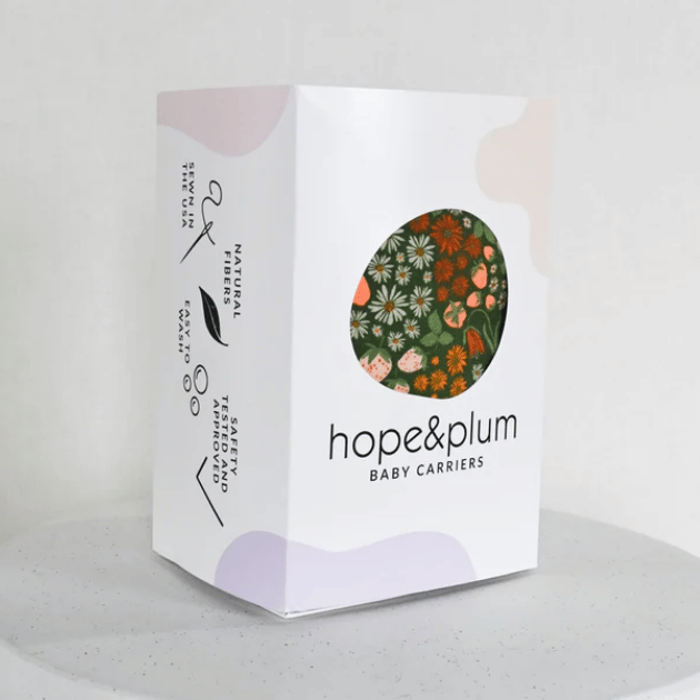 A hope&plum box with a dark green carrier printed with flowers and strawberries visible through a round, asymmetrical window in the front