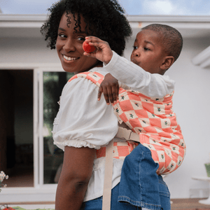 Mid size BIPOC woman wearing a toddler on her back in a hope&plum Darling Kid Lark