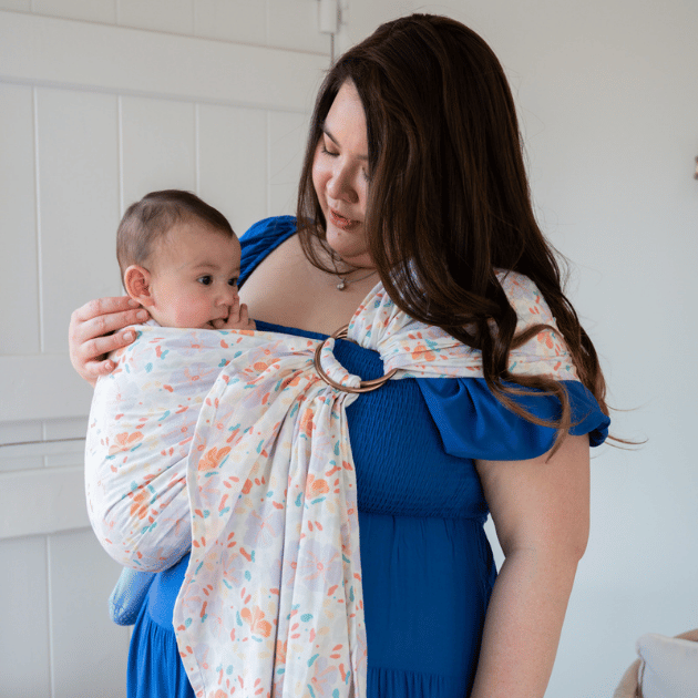 a woman babywearing a hope&plum ring sling in pattern petal