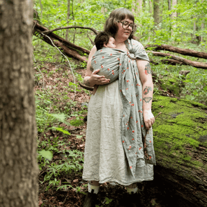 A white plus size woman wears her baby on her front in a hope&plum ring sling