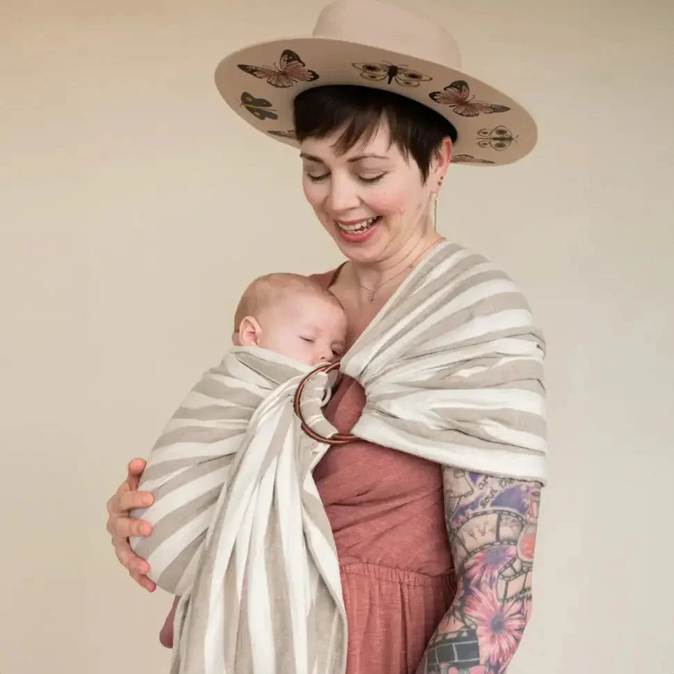 A white straight size woman demonstrates how to use a ring sling in a front carry