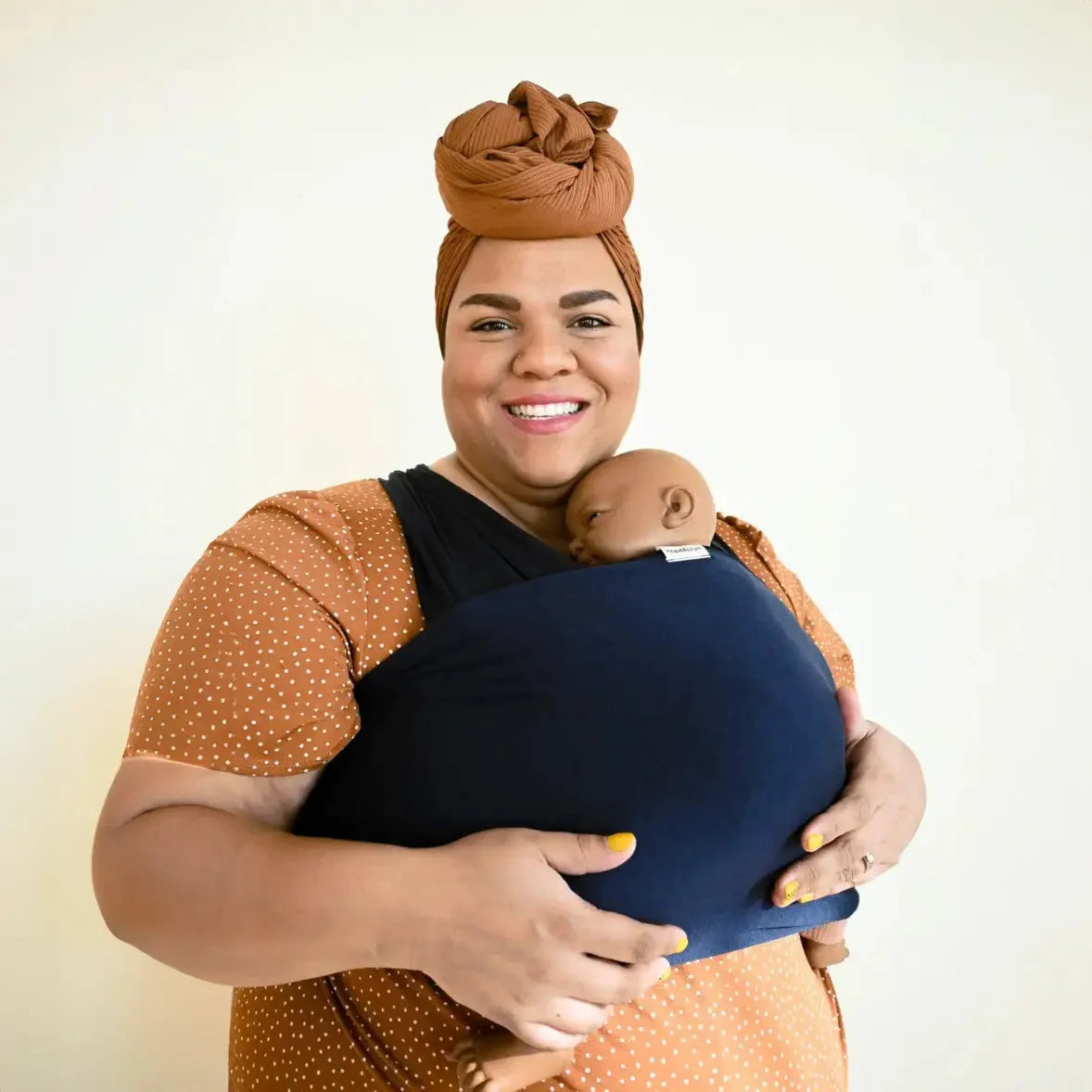 A BIPOC plus size woman wears her baby in a stretchy baby wrap