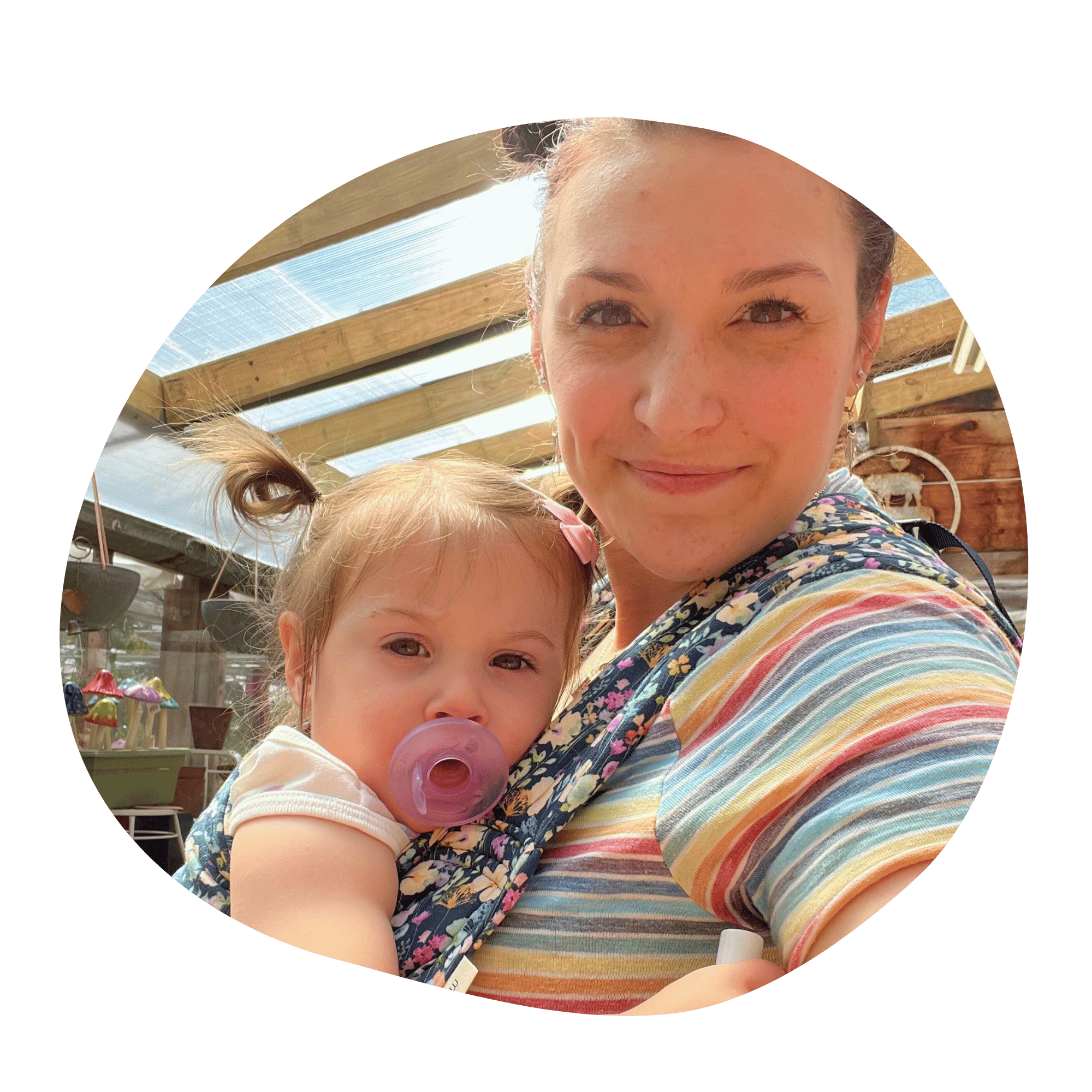 A selfie of a white straight size woman wearing her daughter on her front in an Alice Lark