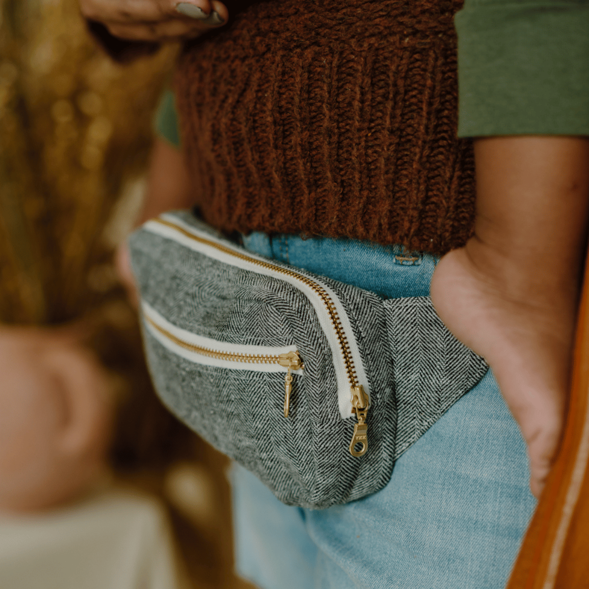 Closeup of a fanny pack around the waist of a Black mom carrying her baby.