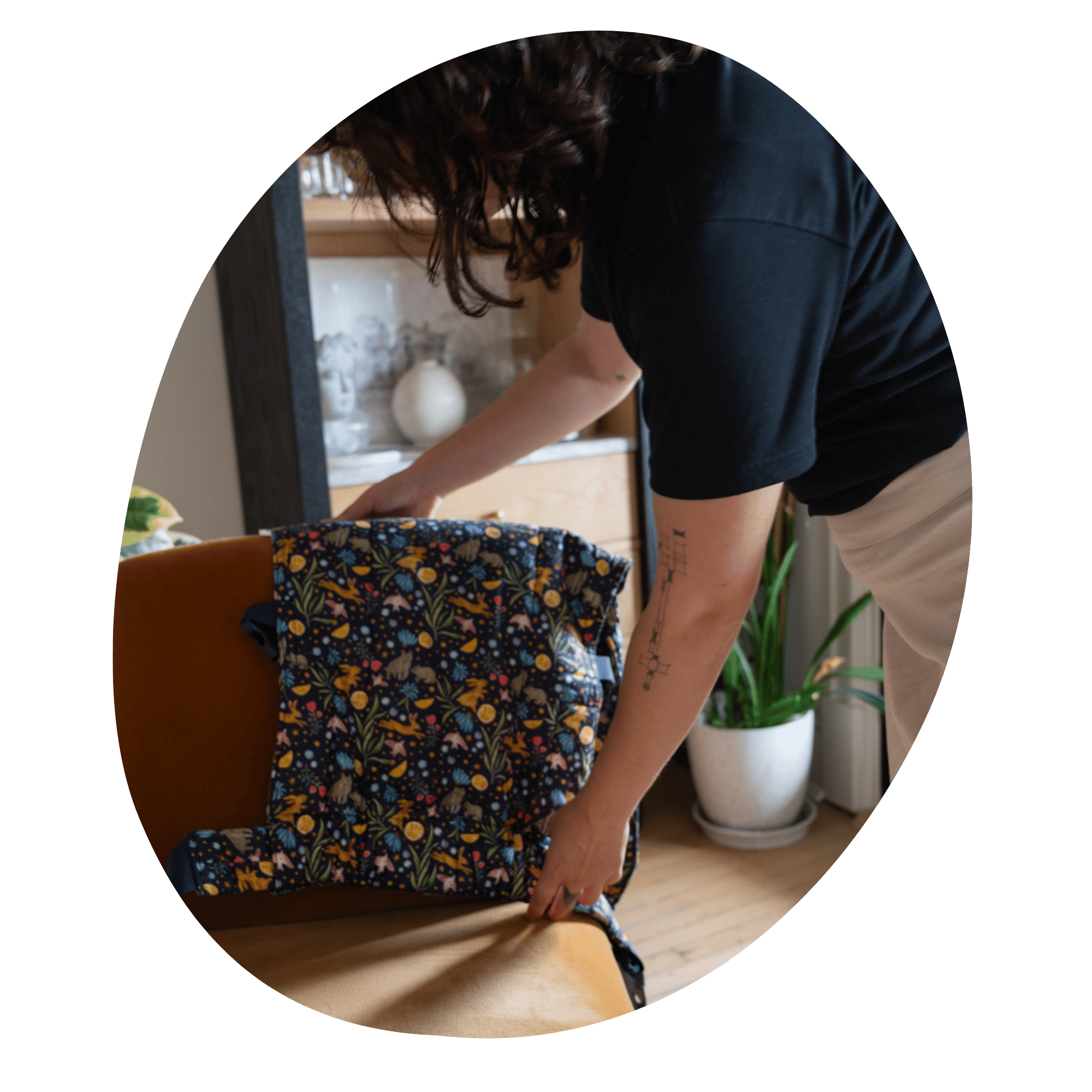 A light-skinned with shoulder-length, dark brown curly hair woman adjusts a Lark that is draped over the back of a chair.
