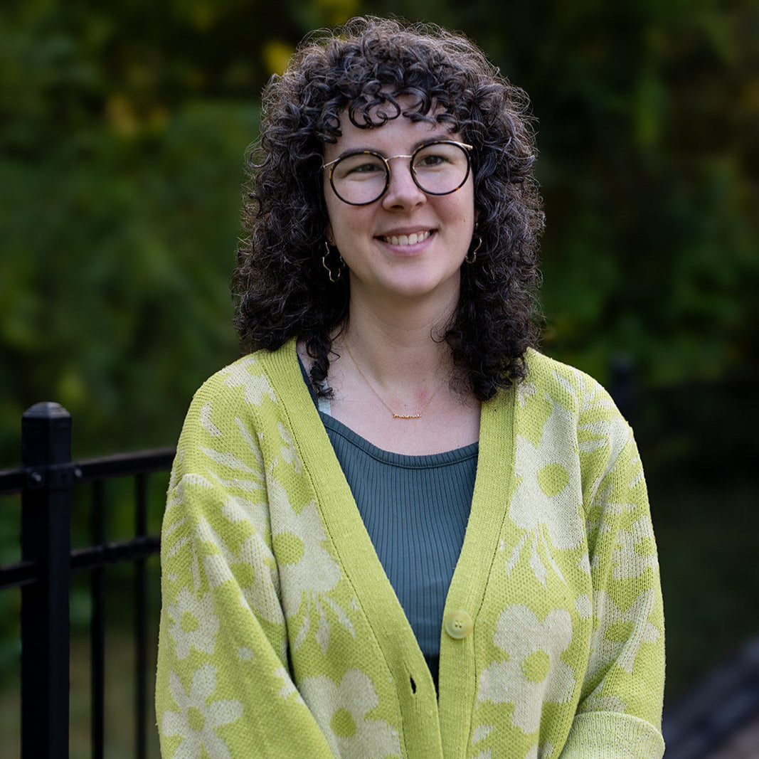 Person wearing a green cardigan standing outdoors with a blurred background