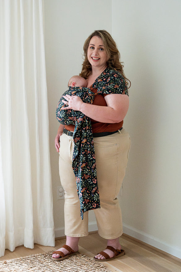 Plus-size mother wearing newborn in moth print long length ring sling