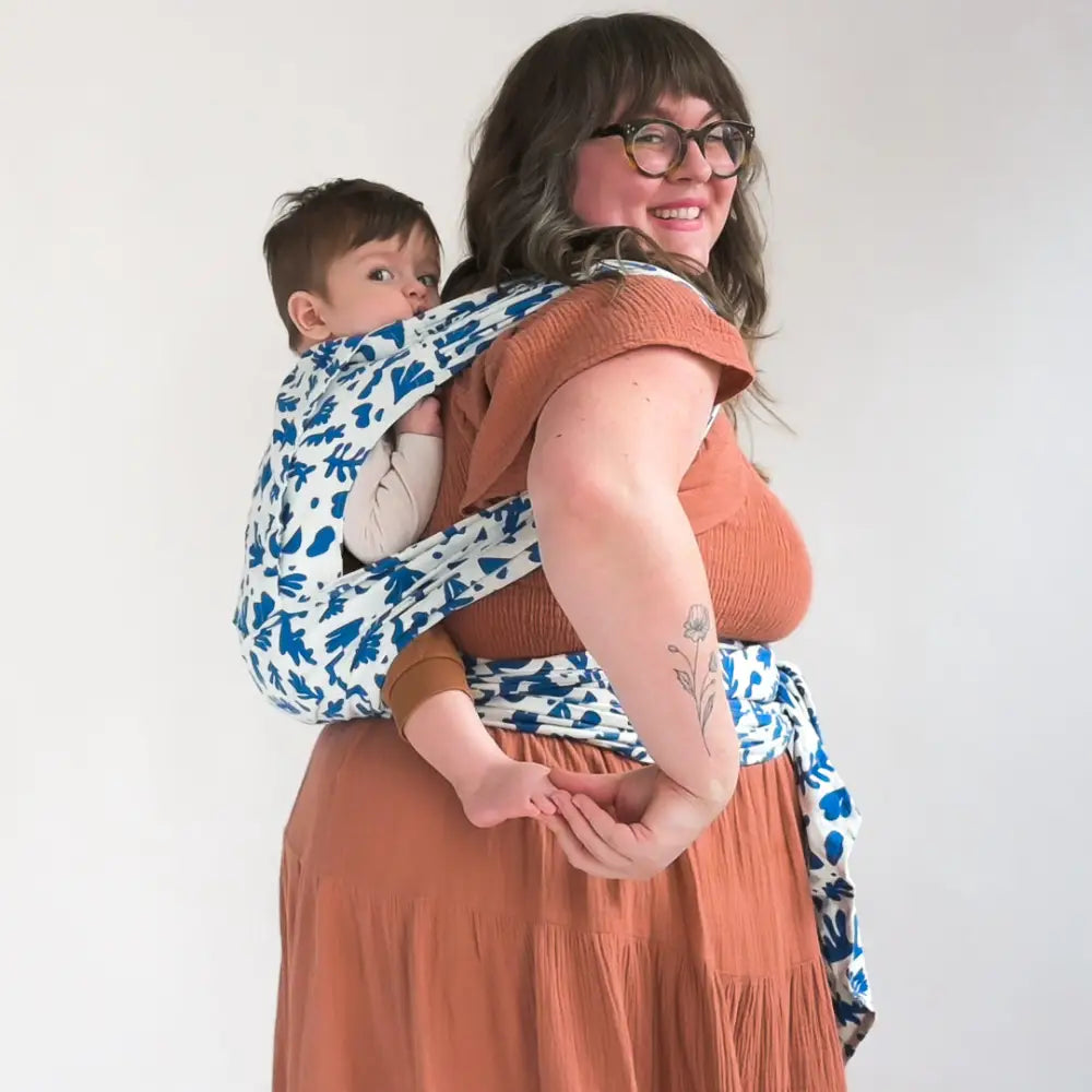 Plus size mother wearing baby on her back in meh dai baby carrier.