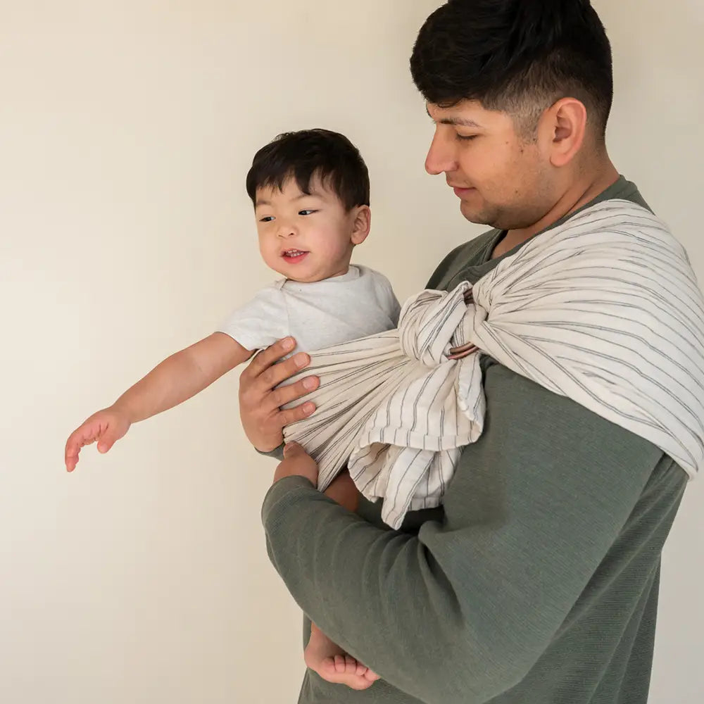 Father wearing white and black stripe ring sling baby carrier.
