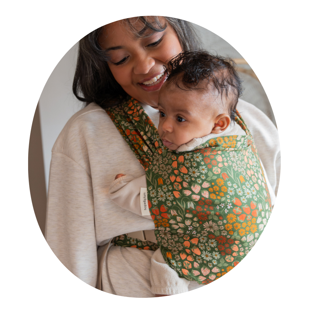 Woman holding baby in strawberry printed newborn carrier