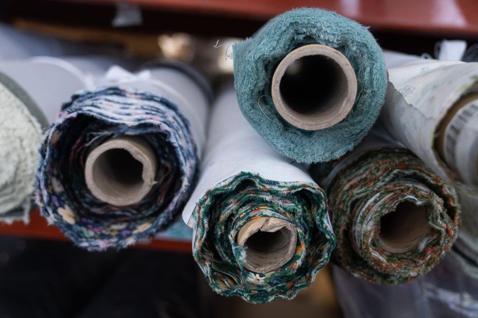 Rolls of fabric in various colors on a wooden surface