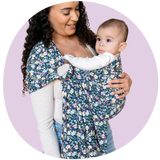 A Black mother smiling at her baby in a baby floral ring sling baby carrier.