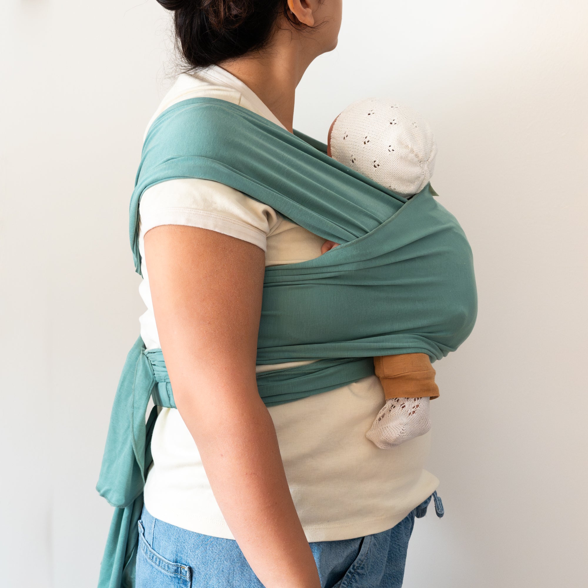 Person wearing a green baby wrap with a white background
