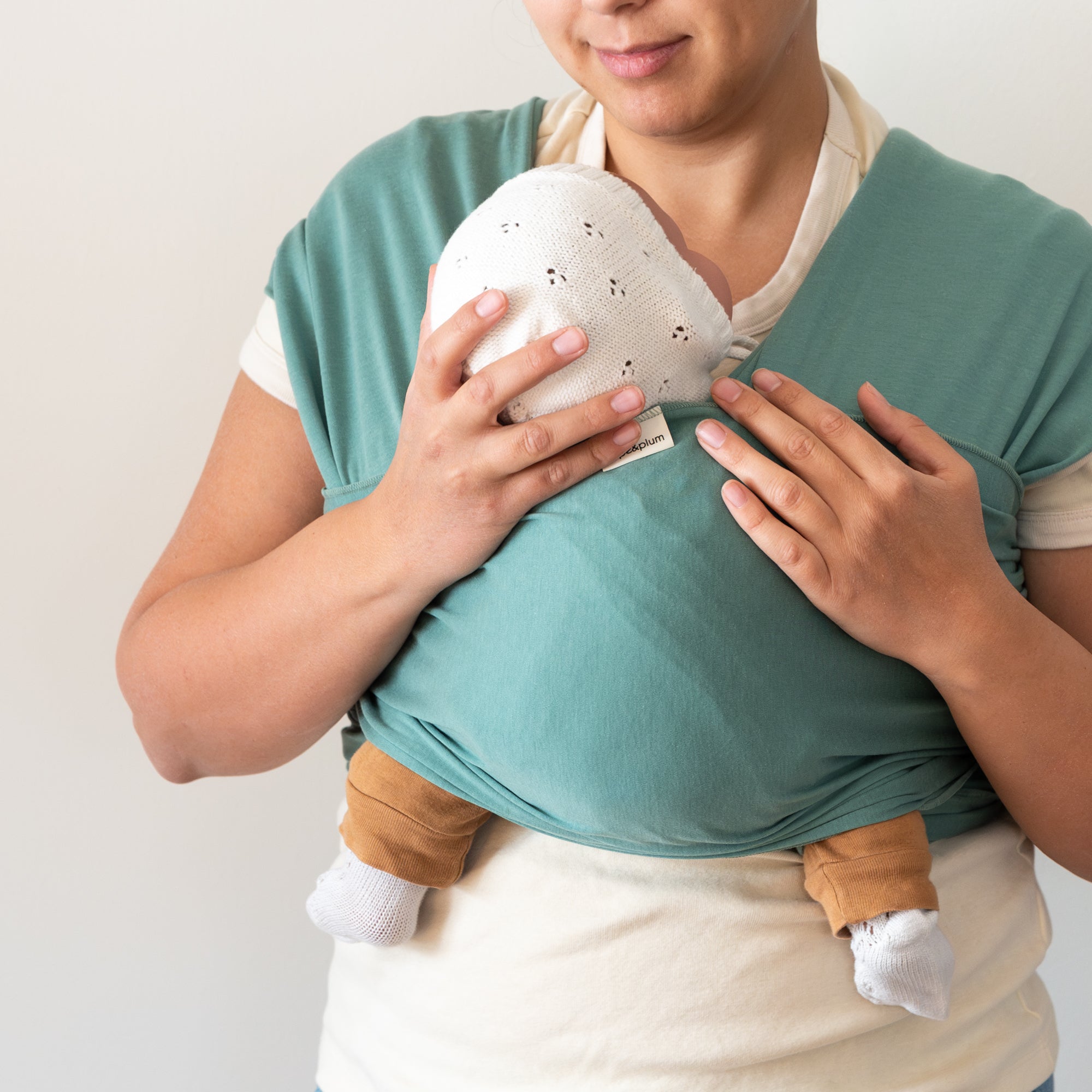 Person wearing a green baby wrap with a white background