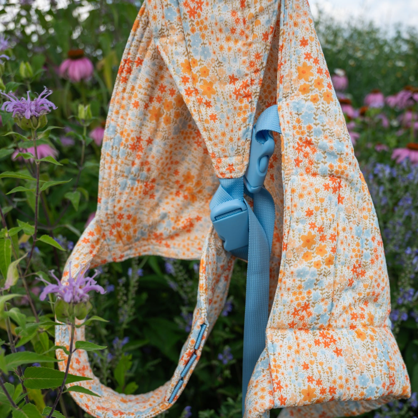Floral-patterned bag with a blue strap against a background of flowers