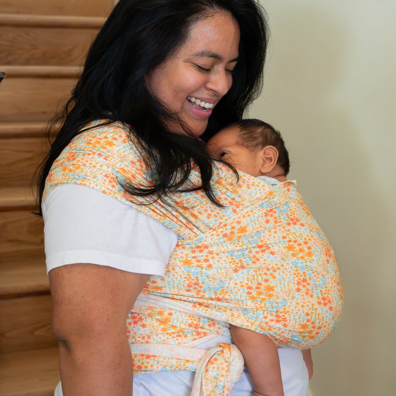 Woman carrying a baby in a wrap at home