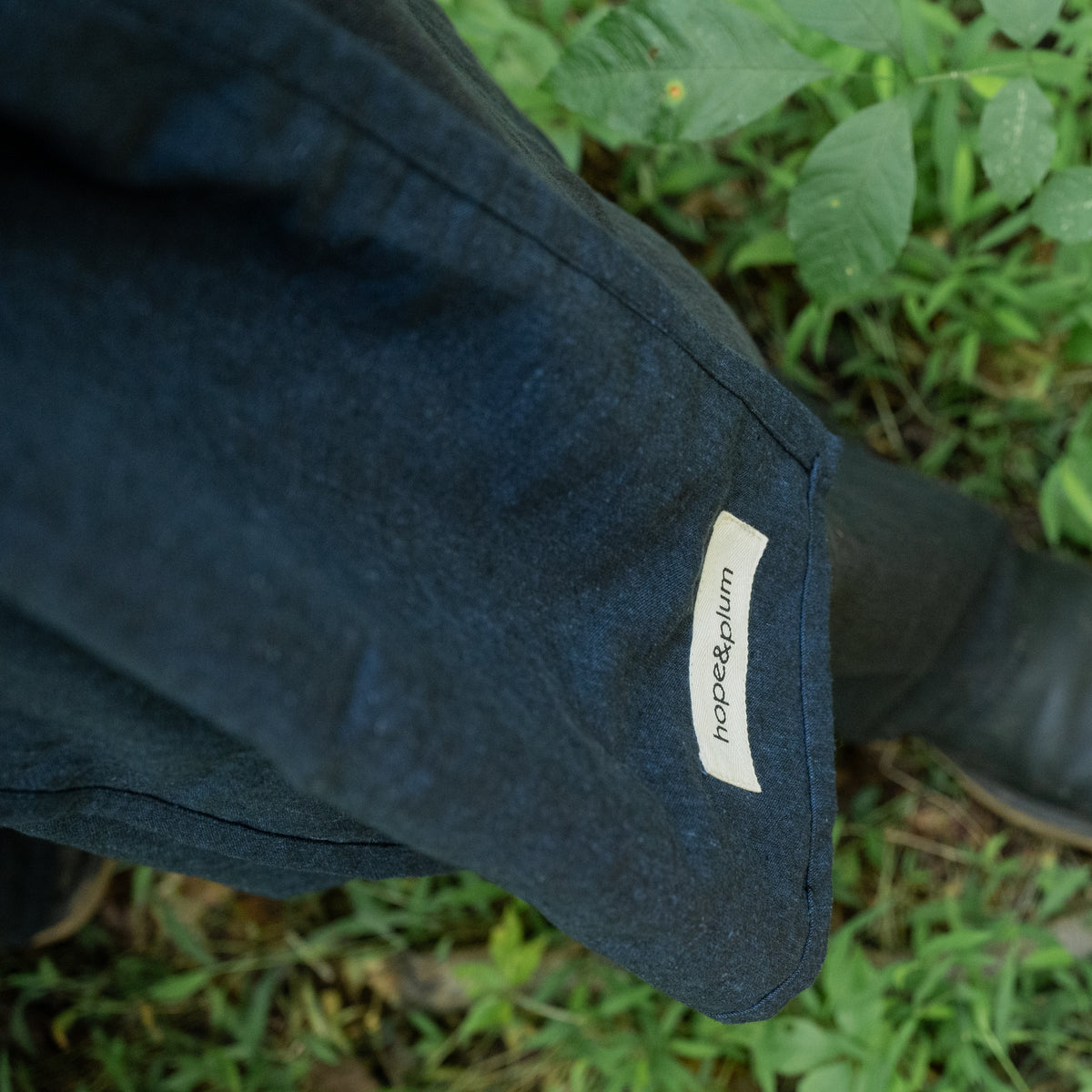 Close view of the Caspian Ring Sling's hemmed tail and hope&plum label, showing the depth and subtle texture of the indigo and black woven chambray.
