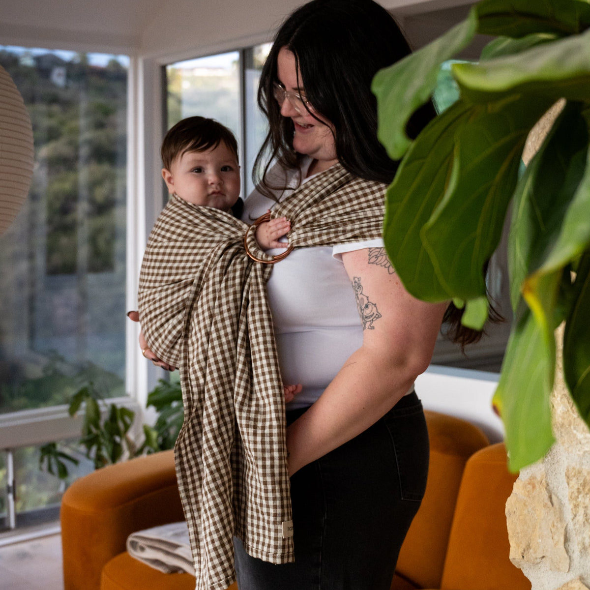 Ring Sling in Clove — caregiver looking down at a baby held in the gingham sling.