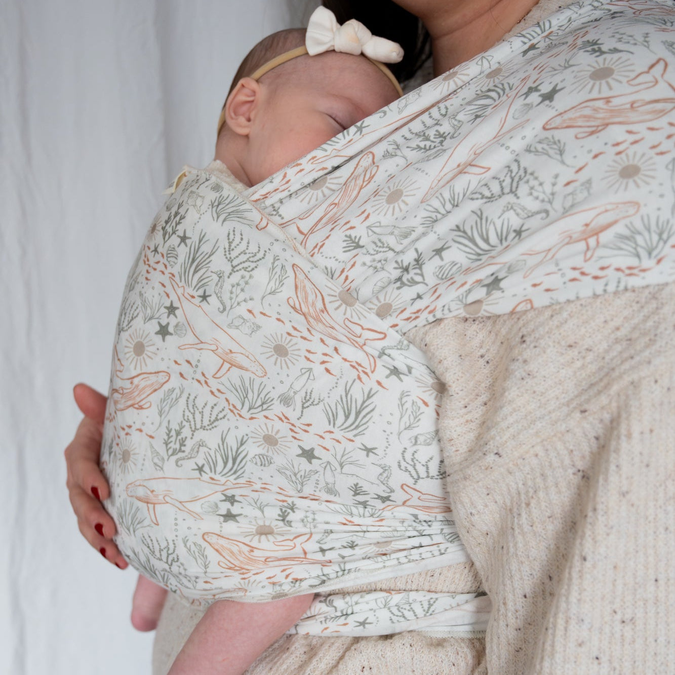 person holding a baby in an ocean print wrap