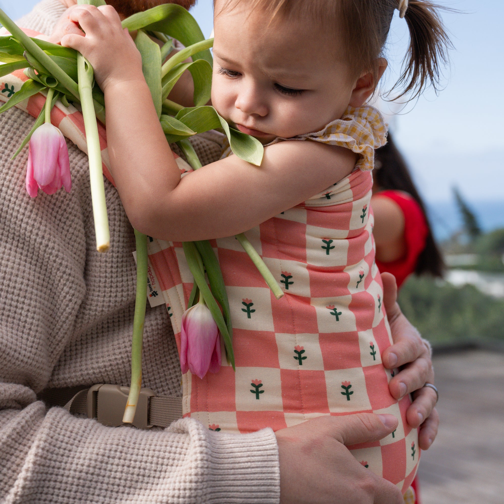 hope&plum Darling Lark buckle baby carrier coral checkerboard with tulips in front carry position