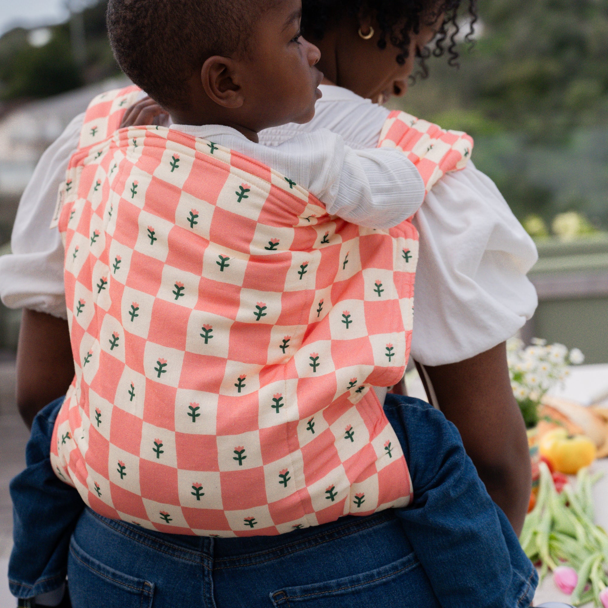 hope&plum Darling Kid Lark toddler carrier coral checkerboard with tulips in back carry position
