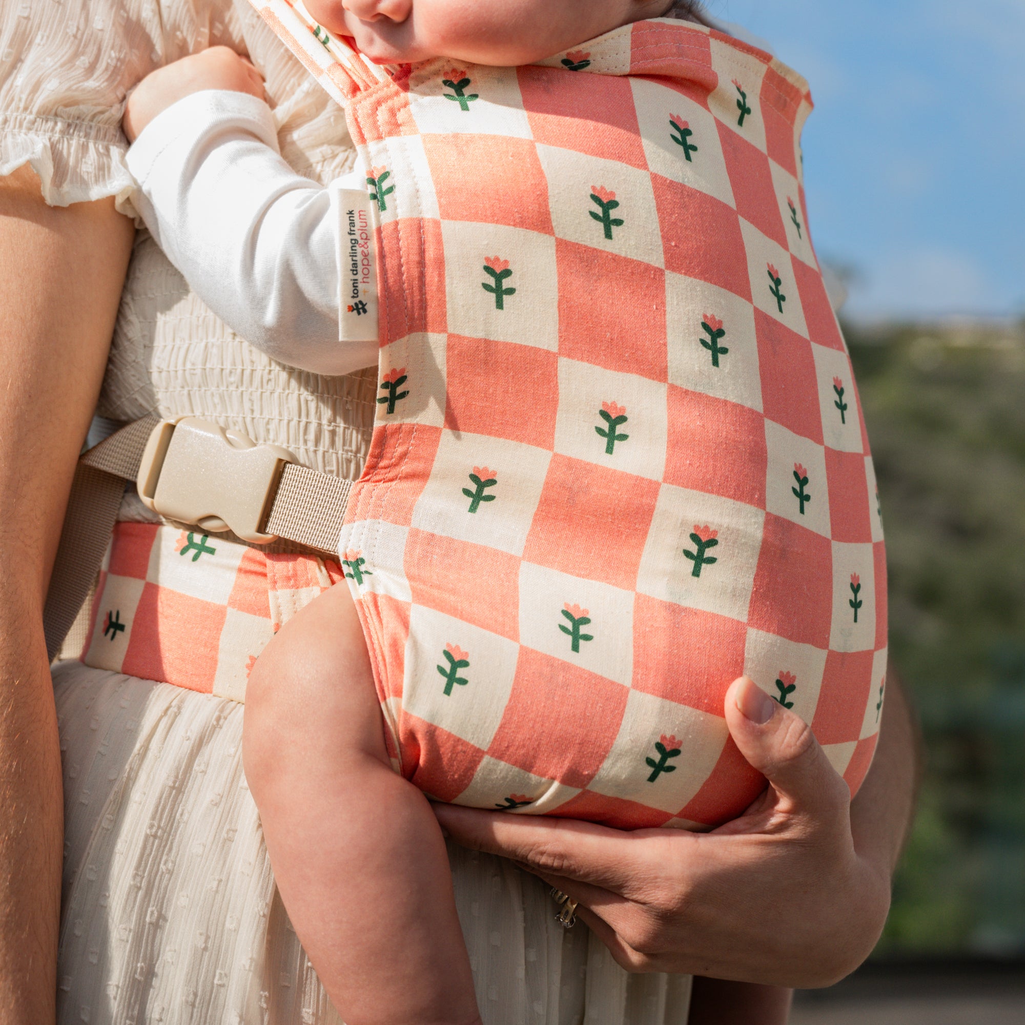 hope&plum Darling Sprout newborn buckle baby carrier coral checkerboard with tulips in front carry position
