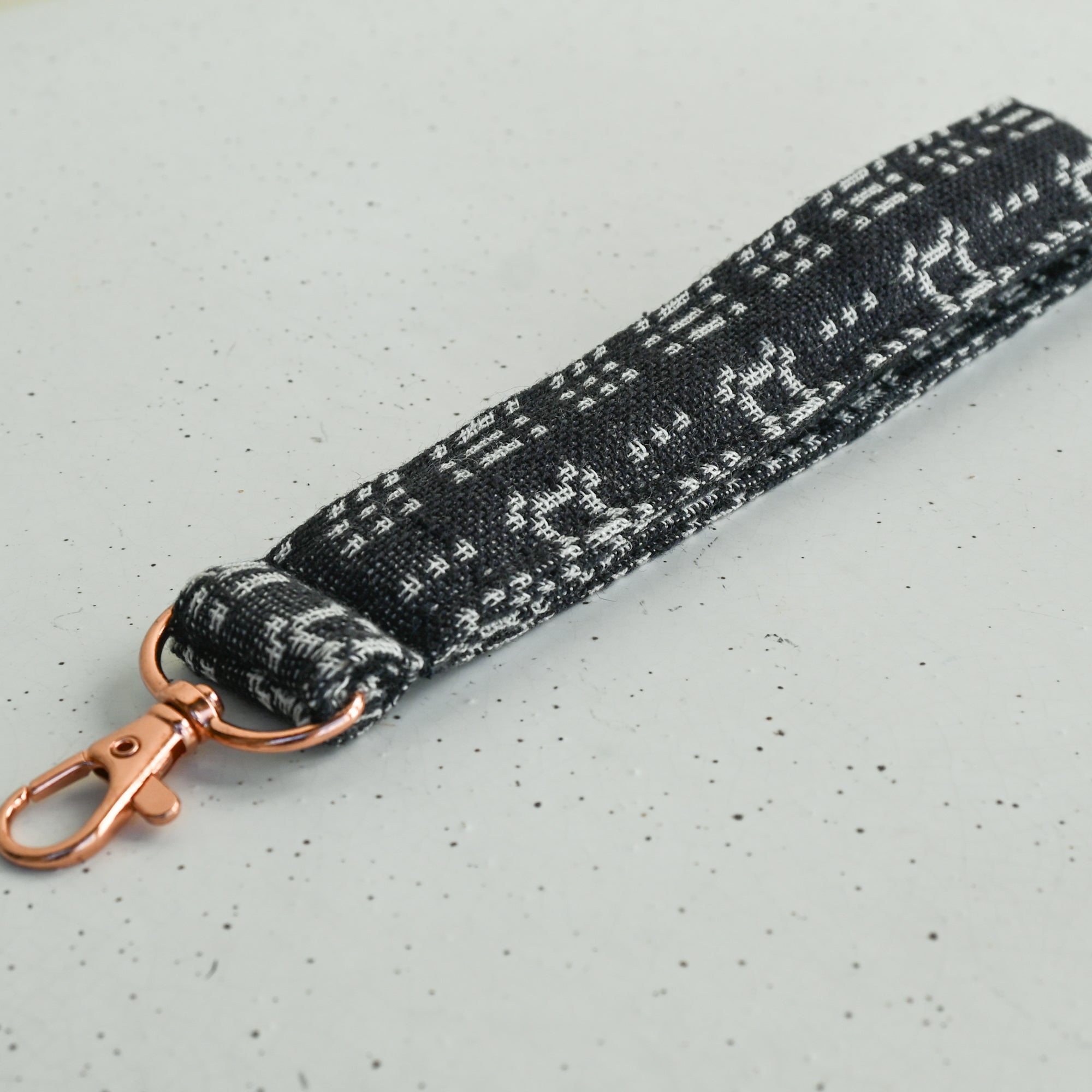 Black and white patterned keychain with rose gold clasp on a white surface