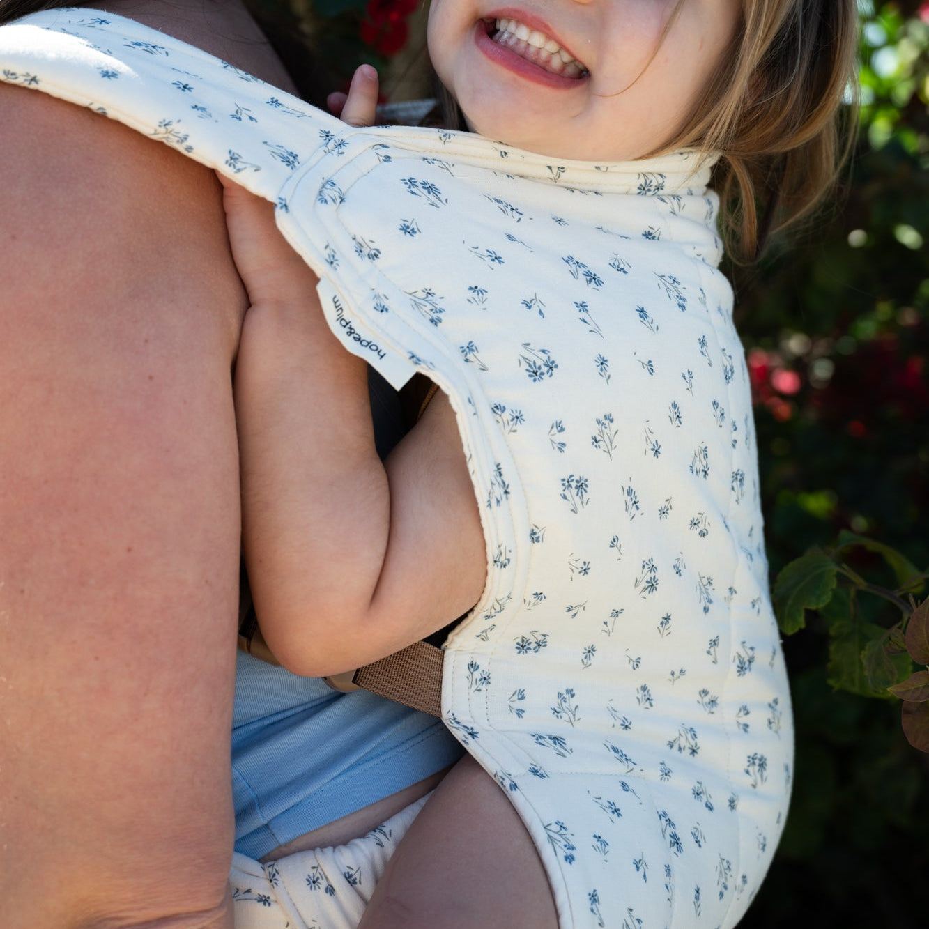 Child in a light floral baby carrier with a florals in the background