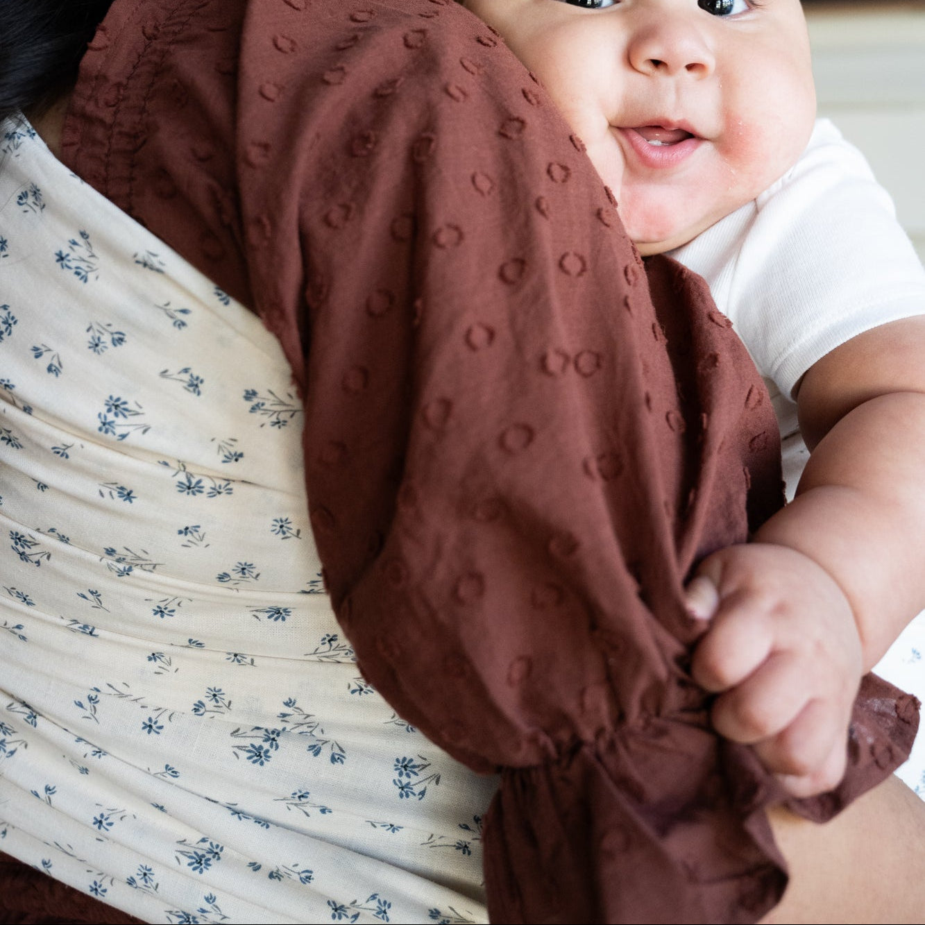 Woman holding a baby wrapped in a dainty floral ring sling