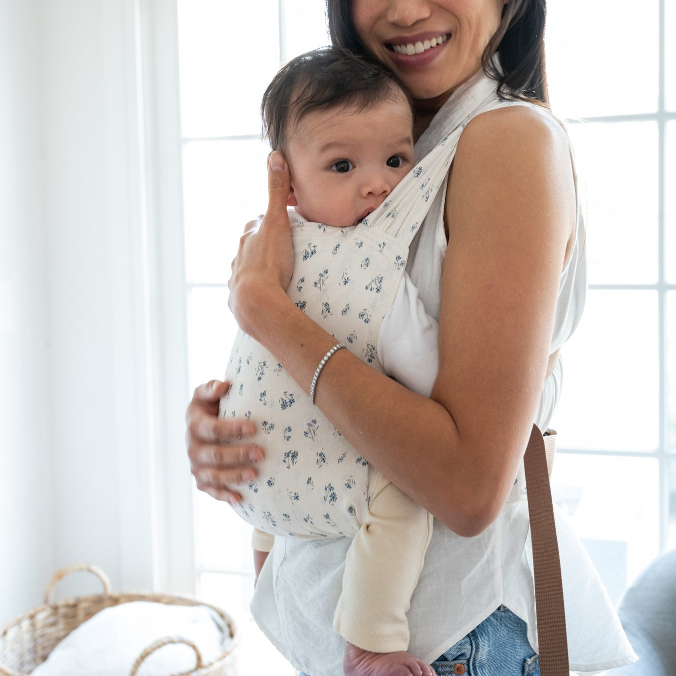 Woman holding a baby in a dainty floral baby carrier.