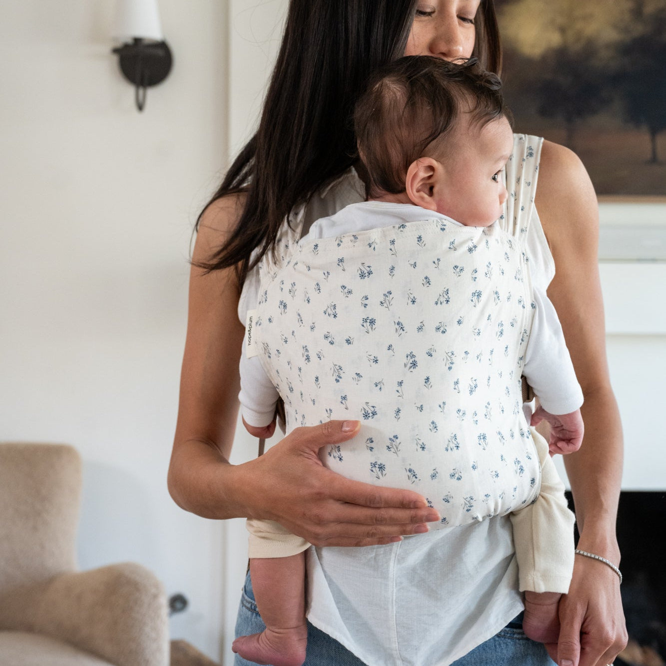 Woman holding a baby in a dainty floral baby carrier.