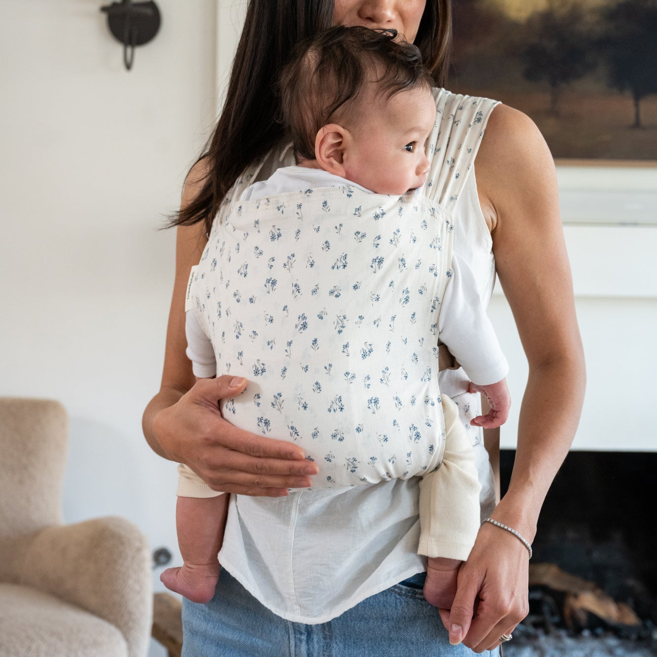 Woman holding a baby in a dainty floral baby carrier.
