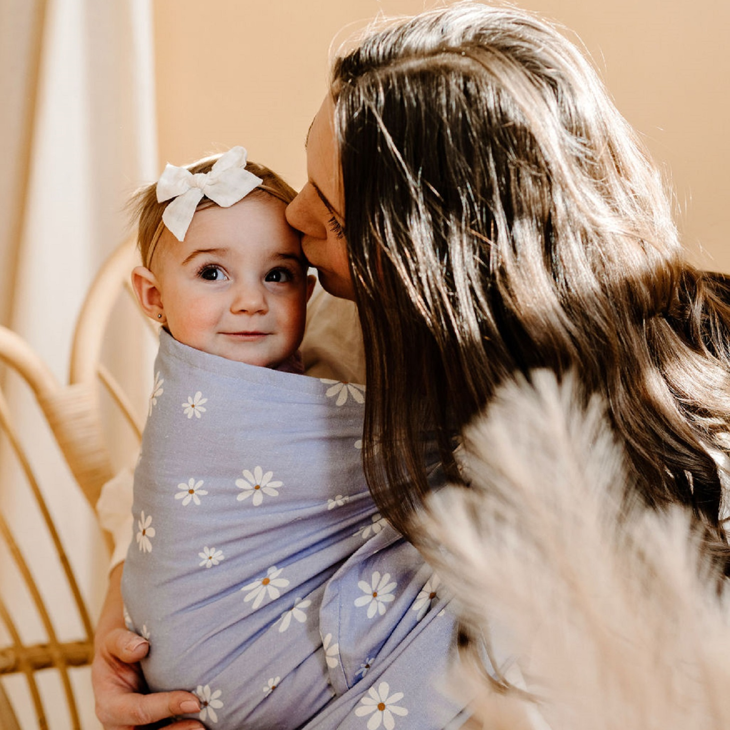White mother holding baby in daisy ring sling.