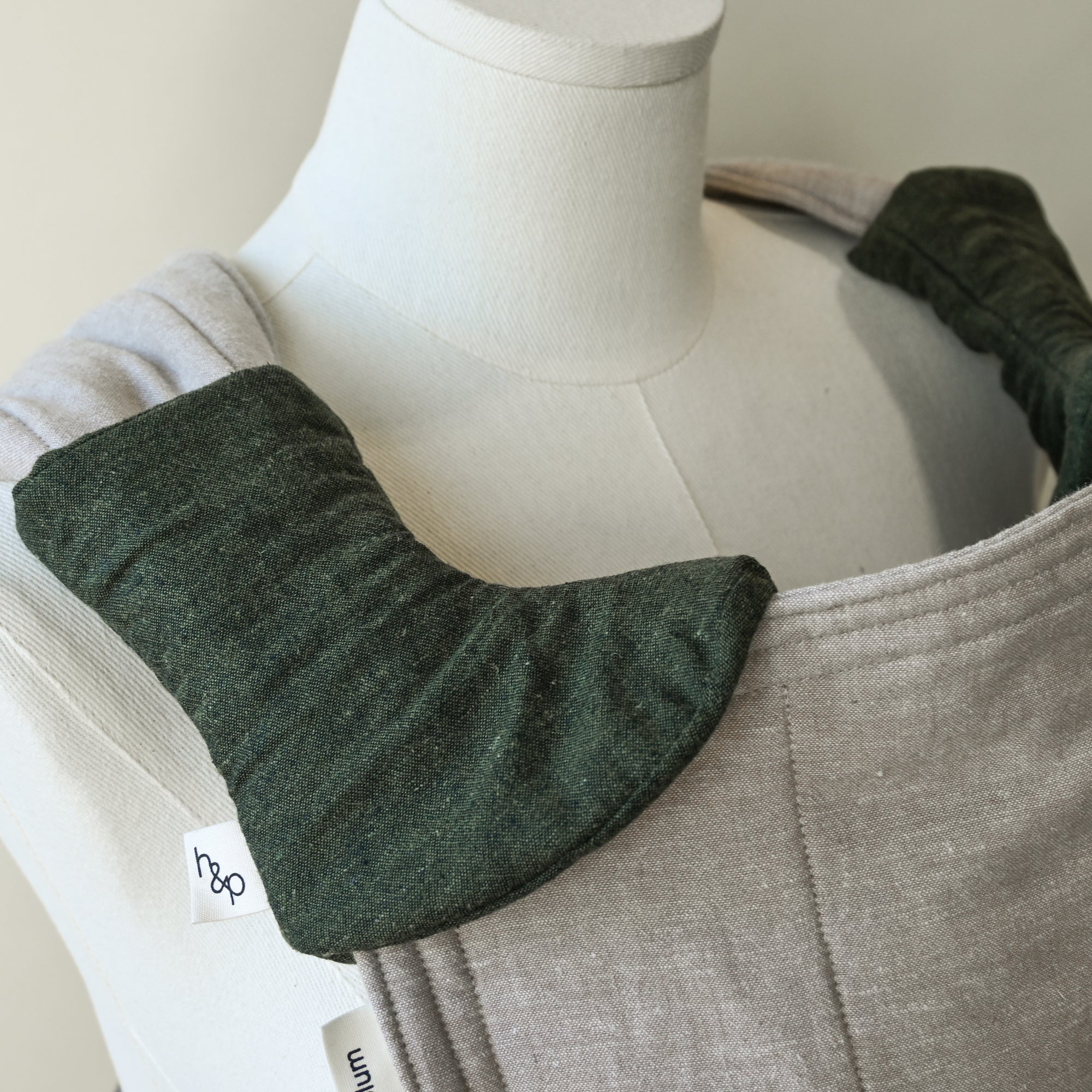 beige carrier with green drool pads on a mannequin