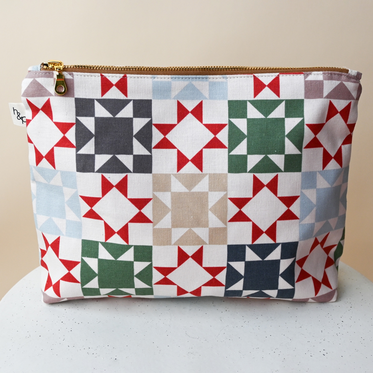 Large Flat Bottom Bag in Heirloom, a standing zip pouch, cream fabric printed with patchwork quilt star blocks in red, green, navy, slate blue and taupe.
