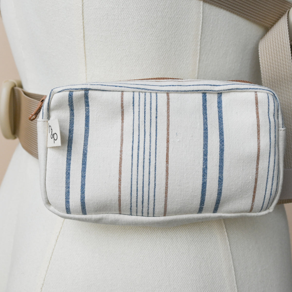 Carrier Pocket in Lugano, a zip pouch on a carrier waistband shown on a dress form, cream woven chambray with blue stripes and fine rust pinstripes.
