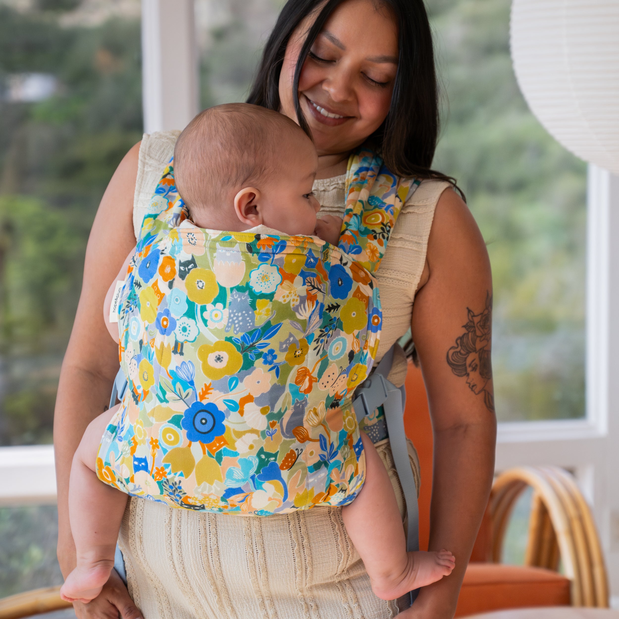 Woman holding a baby in a floral baby carrier