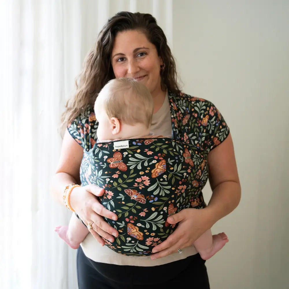 Mother wearing infant in moth print baby wrap carrier.