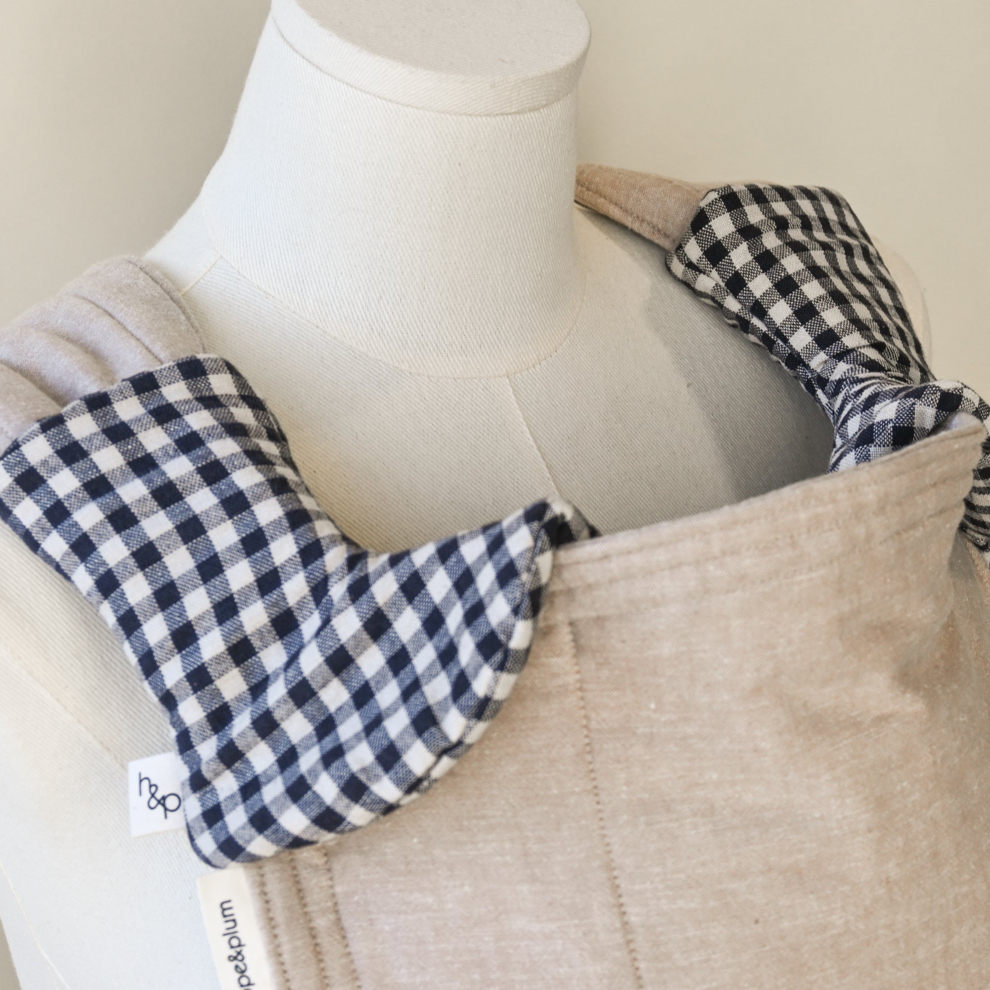 black and white gingham drool pads on a beige carrier