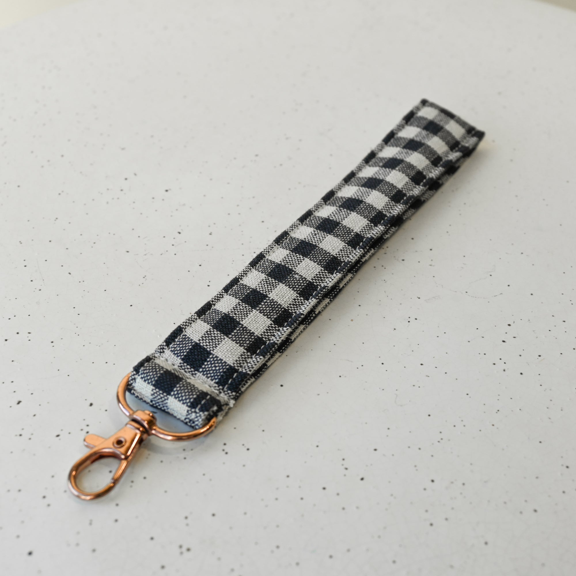 Black and white gingham keychain strap on a speckled white surface