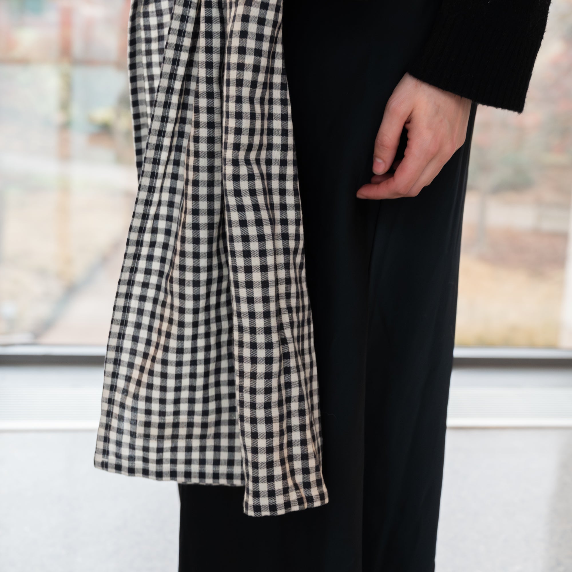 Woman holding a baby in a black and white gingham patterned ring sling