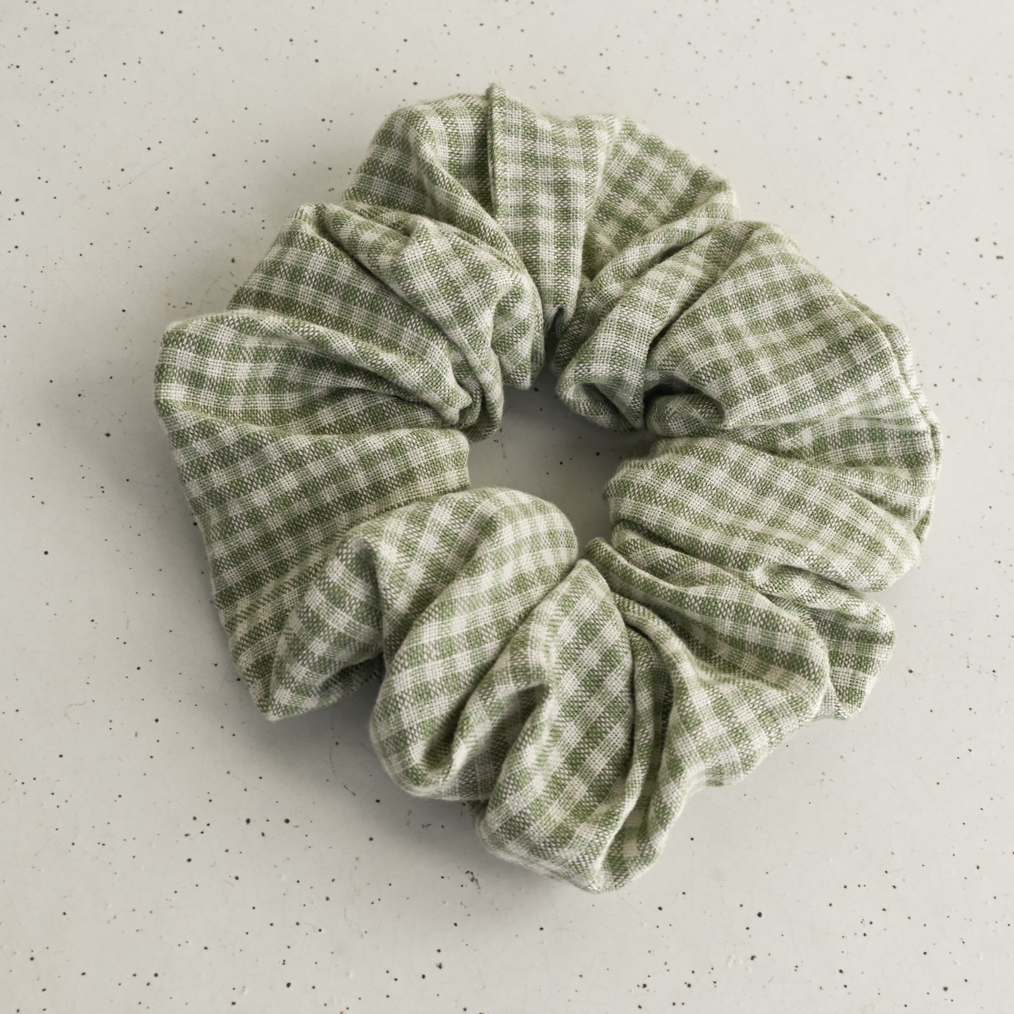 Green gingham scrunchie on a white speckled surface