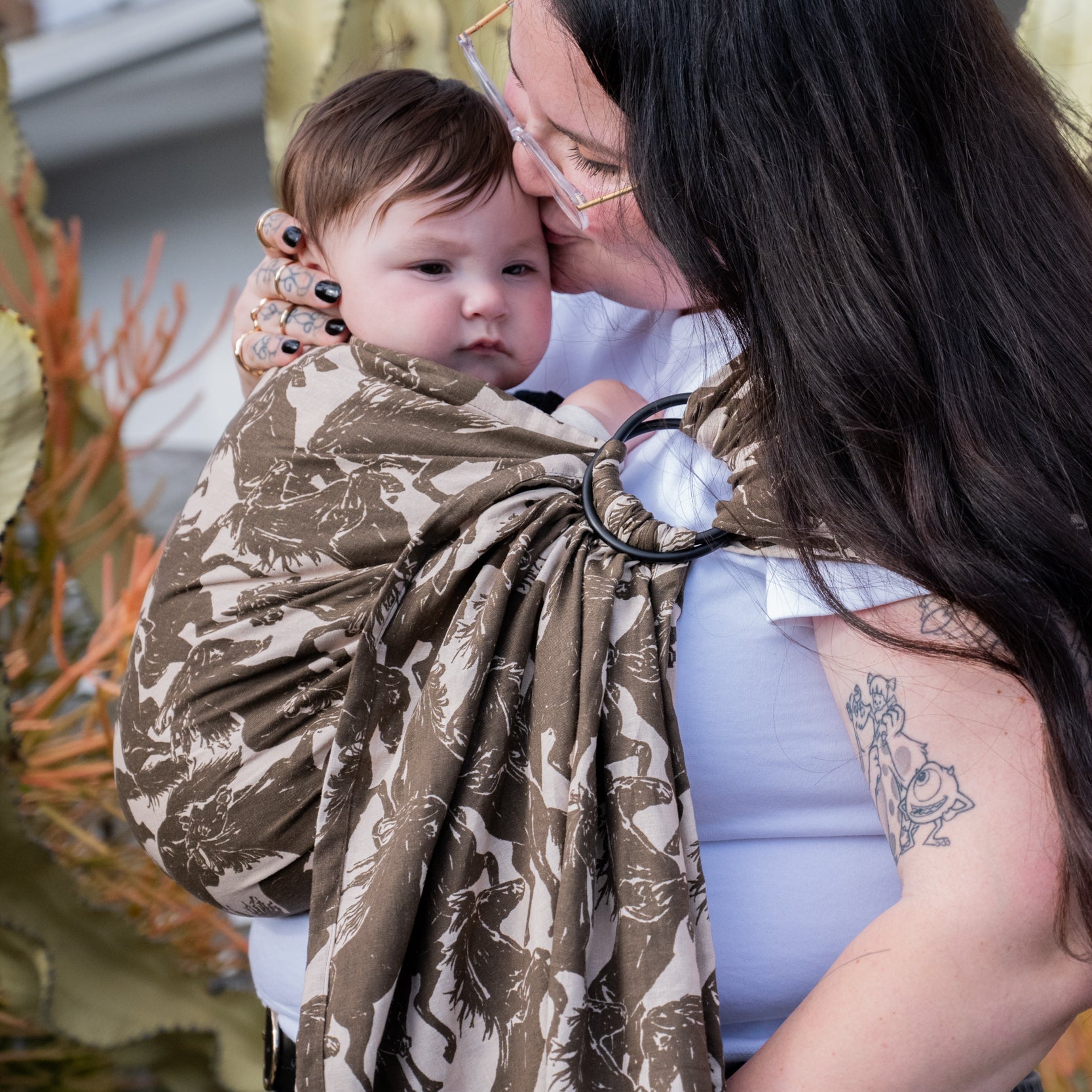 Ring Sling in Rodeo — close-up of a baby peeking over the edge of the mustang print sling fabric.