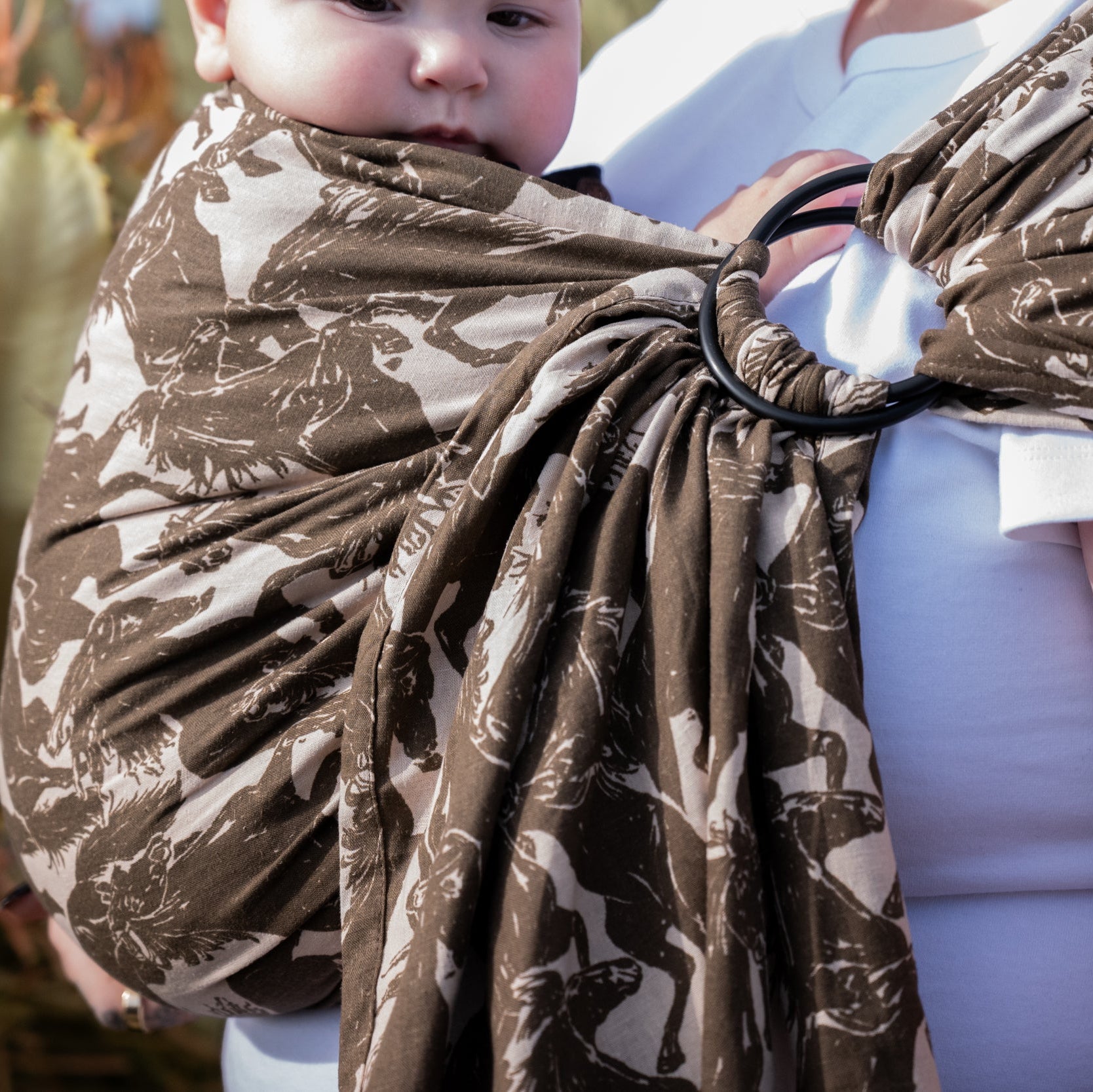 Ring Sling in Rodeo — close-up of the gathered rings and draped mustang print fabric, baby tucked inside.