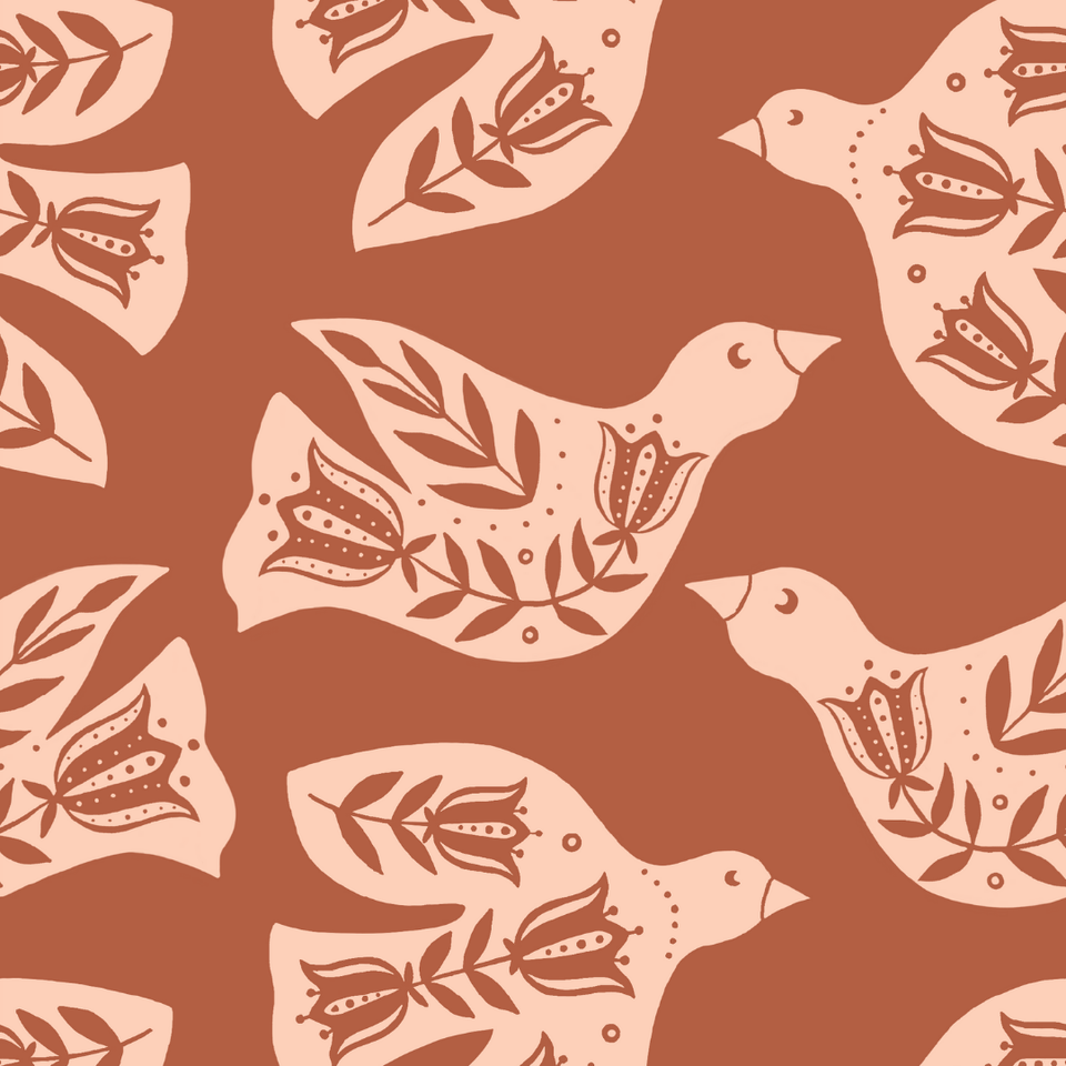 A folk-art fabric print on a warm rust-terracotta background featuring large stylized doves in soft blush, their bodies decorated with darker tonal motifs of leafy branches and tulip-like flowers. The birds face different directions in a balanced, repeating composition. Bold, graphic, and Scandinavian-folk inspired, with a vintage block-print feel.
